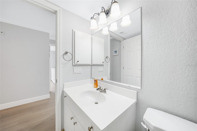 bathroom featuring hardwood / wood-style flooring, vanity, toilet, and a notable chandelier