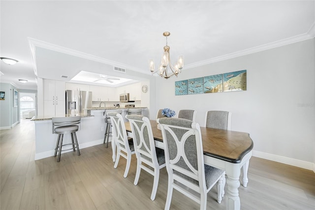 dining room with crown molding, light hardwood / wood-style floors, and a notable chandelier