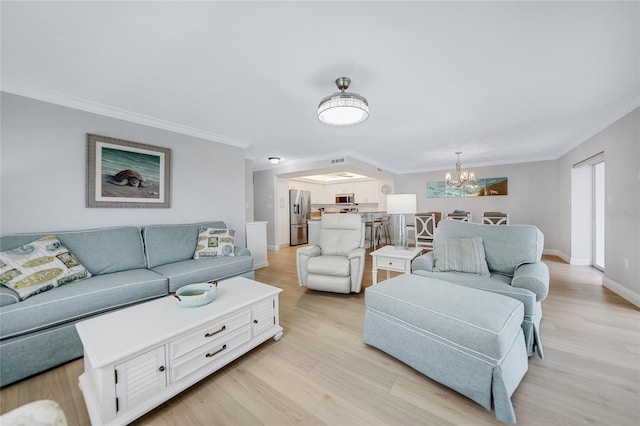 living room featuring a chandelier, light hardwood / wood-style floors, and ornamental molding