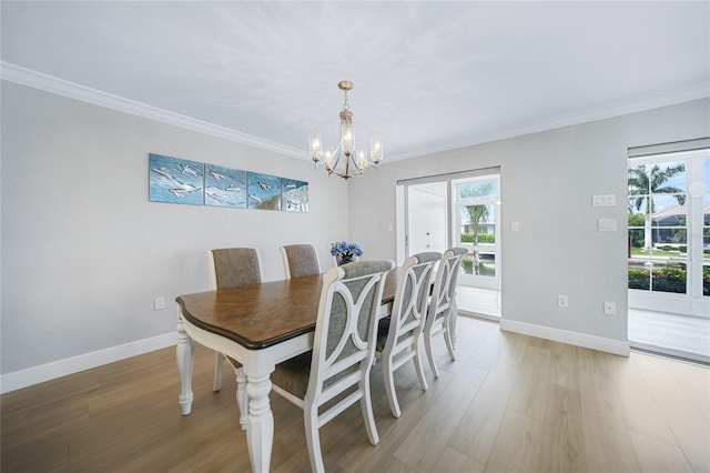 dining space featuring crown molding, light wood-type flooring, and a notable chandelier