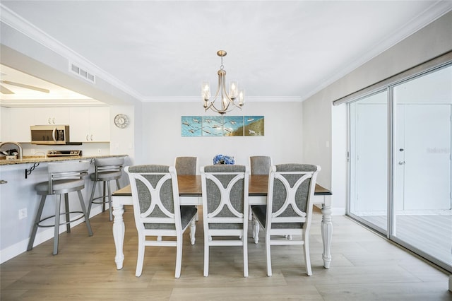 dining space featuring crown molding, light wood-type flooring, and a notable chandelier