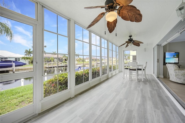 sunroom / solarium with ceiling fan, a water view, and a healthy amount of sunlight