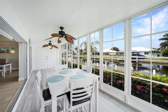 sunroom with a water view and ceiling fan