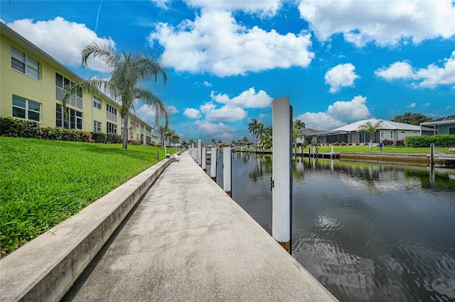 view of dock featuring a lawn and a water view