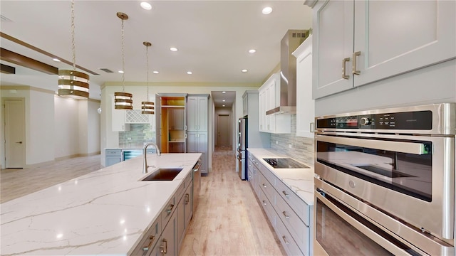 kitchen featuring appliances with stainless steel finishes, decorative backsplash, hanging light fixtures, light stone counters, and sink