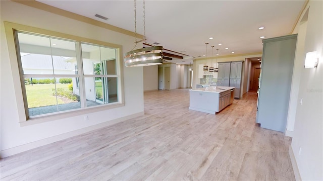 kitchen featuring light wood-type flooring, sink, pendant lighting, and a center island