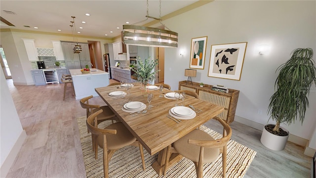 dining room with beverage cooler and light hardwood / wood-style flooring