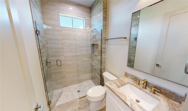 bathroom featuring toilet, a shower with shower door, and vanity