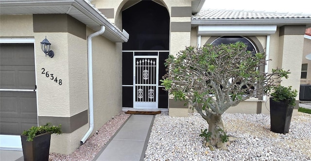 view of exterior entry with central air condition unit and a garage