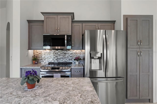 kitchen with light stone countertops, appliances with stainless steel finishes, and tasteful backsplash