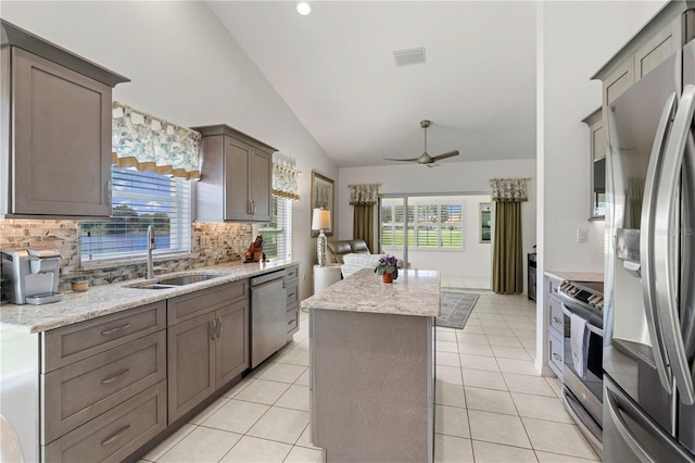 kitchen with tasteful backsplash, stainless steel appliances, vaulted ceiling, sink, and a kitchen island