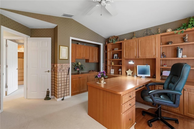 office space featuring light carpet, ceiling fan, and built in desk