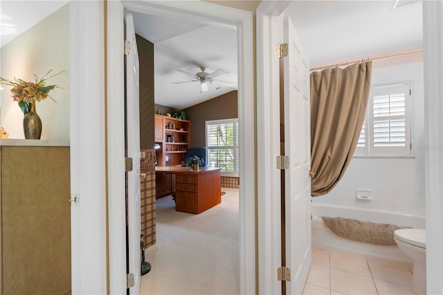 interior space featuring lofted ceiling, tile patterned floors, ceiling fan, toilet, and shower / tub combo with curtain