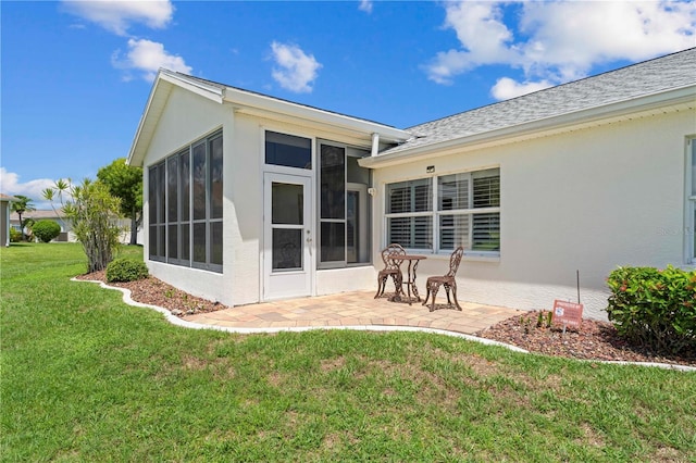 rear view of property with a yard, a patio, and a sunroom