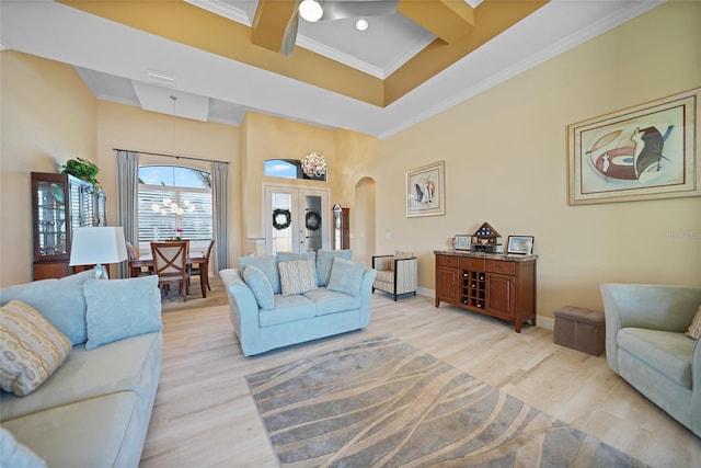 living room with ceiling fan, light hardwood / wood-style flooring, a high ceiling, and ornamental molding