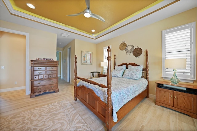 bedroom with ceiling fan, light wood-type flooring, ornamental molding, and a tray ceiling