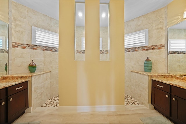 bathroom with vanity, tile walls, and walk in shower