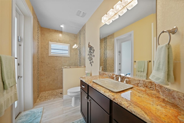 bathroom featuring tiled shower, vanity, and toilet