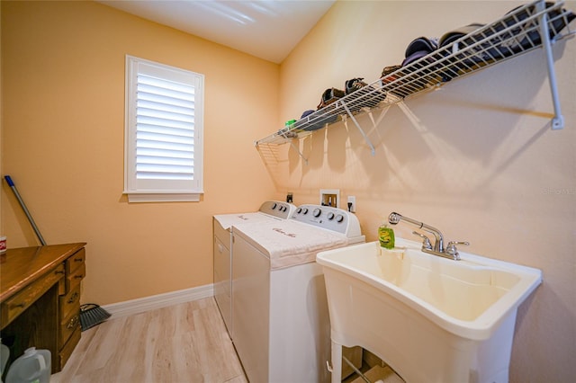 washroom featuring washing machine and clothes dryer, sink, and light hardwood / wood-style floors