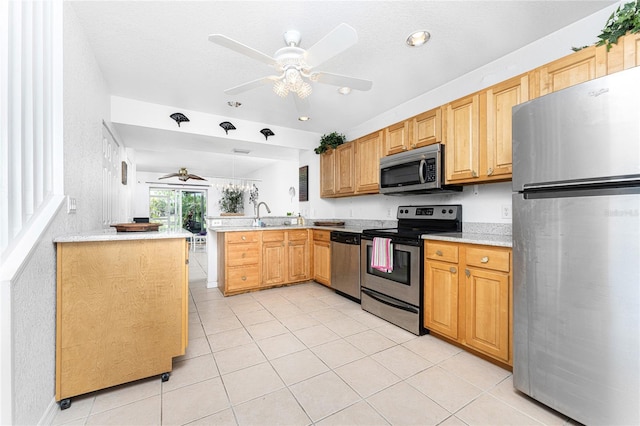 kitchen with sink, ceiling fan, light tile patterned floors, kitchen peninsula, and stainless steel appliances