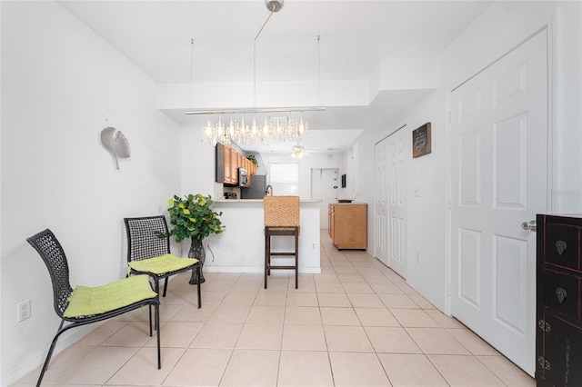 kitchen with kitchen peninsula, ceiling fan, a breakfast bar area, and light tile patterned flooring