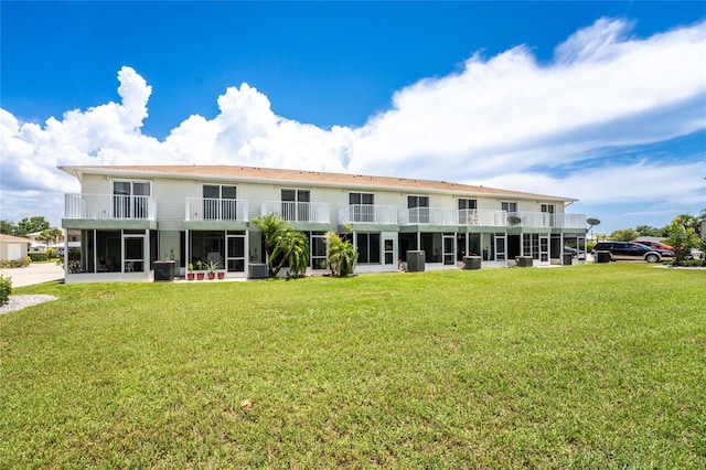 back of property with a yard, central AC, and a balcony