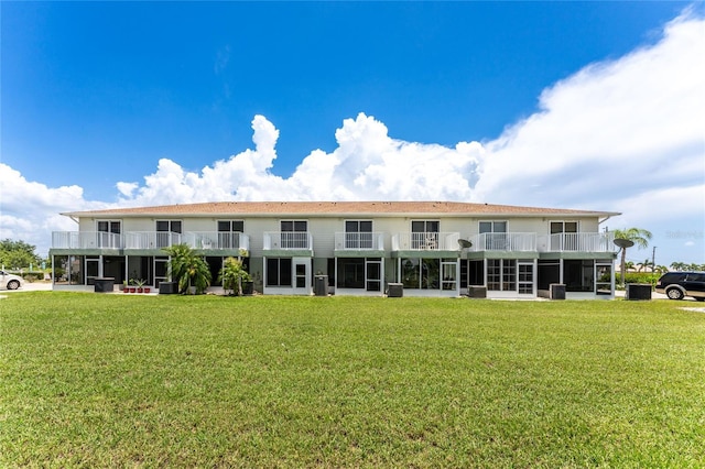 rear view of property with a balcony and a yard