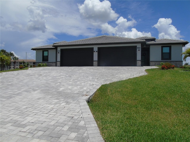 prairie-style house featuring stucco siding, an attached garage, and decorative driveway