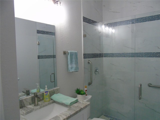 full bathroom featuring vanity, a shower stall, and toilet