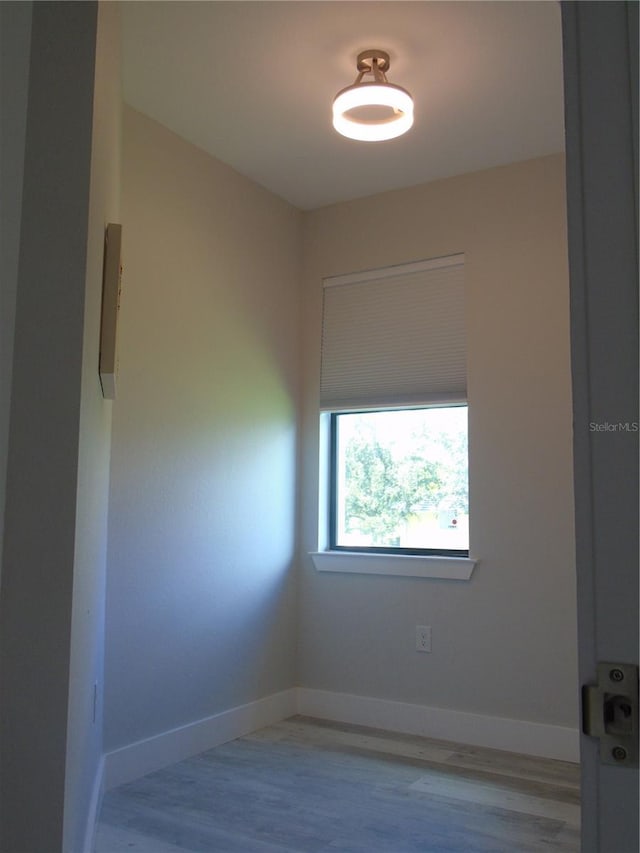 spare room with baseboards and wood finished floors