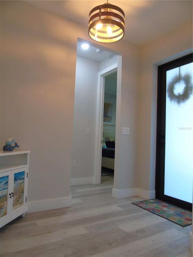 entrance foyer with a notable chandelier, light wood-style floors, and baseboards