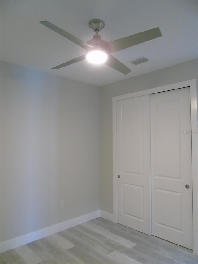 unfurnished bedroom featuring a closet, light hardwood / wood-style flooring, and ceiling fan