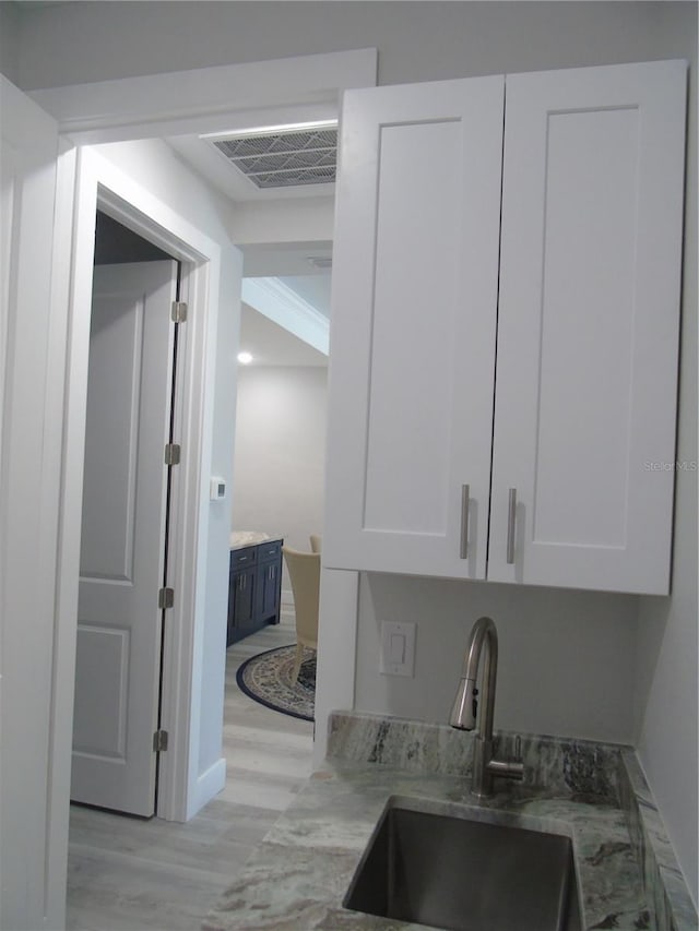 bar featuring a sink, visible vents, and light wood-type flooring