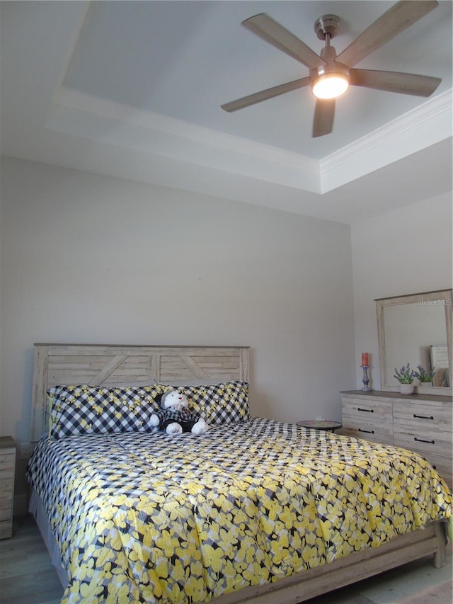 bedroom featuring a raised ceiling, a ceiling fan, and ornamental molding