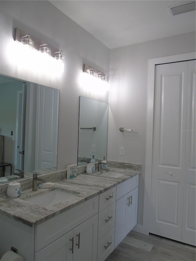 full bathroom with double vanity, wood finished floors, visible vents, and a sink