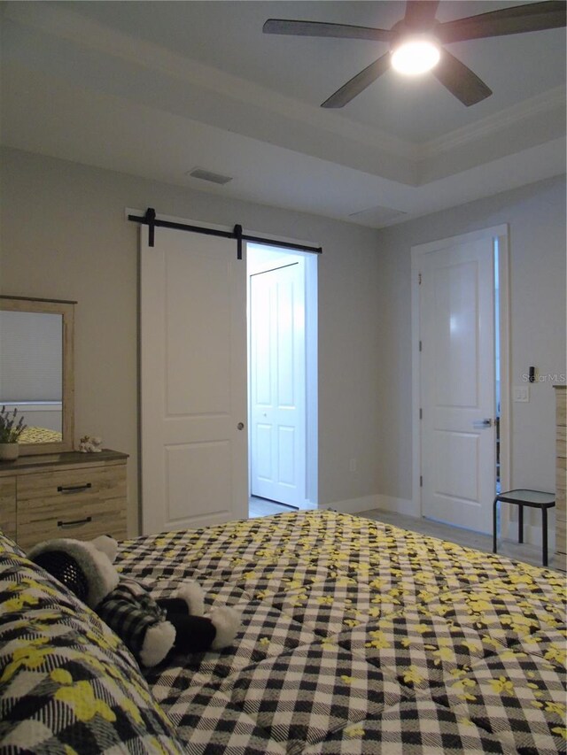 bedroom featuring a ceiling fan, visible vents, a tray ceiling, a barn door, and carpet flooring