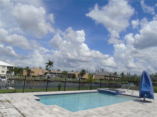 view of pool featuring a patio area, an in ground hot tub, and a water view