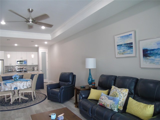 living room featuring a tray ceiling, crown molding, ceiling fan, and light hardwood / wood-style floors