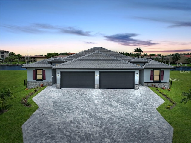 view of front facade featuring stucco siding, an attached garage, stone siding, and a front lawn