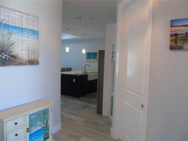 corridor with a sink and light wood finished floors