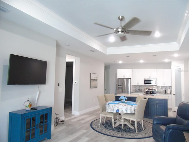 dining area with ornamental molding, visible vents, a ceiling fan, and a raised ceiling