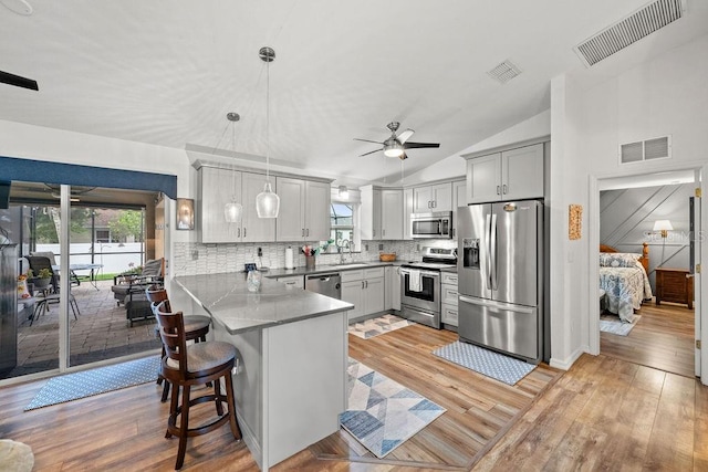 kitchen featuring decorative light fixtures, ceiling fan, light hardwood / wood-style floors, appliances with stainless steel finishes, and kitchen peninsula