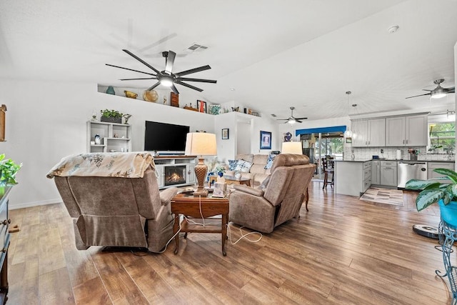 living room with lofted ceiling, ceiling fan, and light hardwood / wood-style flooring