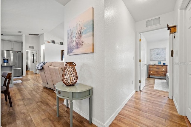 hallway with vaulted ceiling and light hardwood / wood-style floors