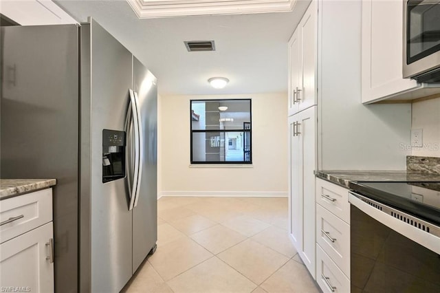 kitchen with crown molding, dark stone countertops, stainless steel appliances, white cabinets, and light tile floors