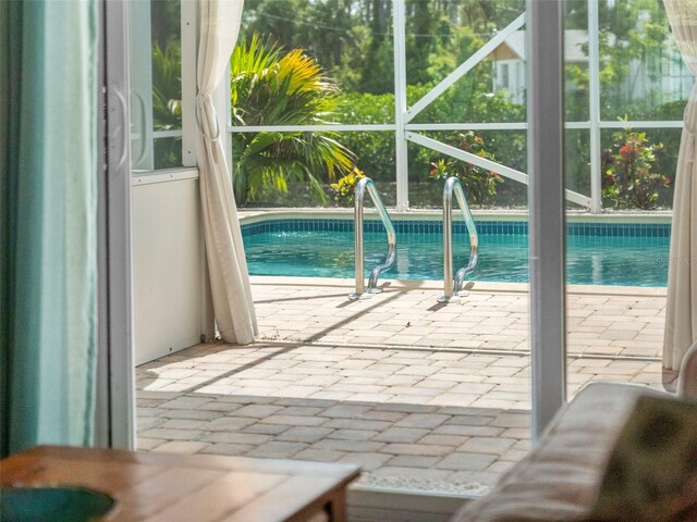 view of pool with a patio area and glass enclosure