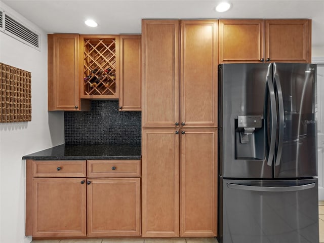 kitchen with decorative backsplash, dark stone counters, and stainless steel refrigerator with ice dispenser