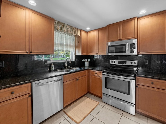 kitchen with appliances with stainless steel finishes, sink, light tile patterned floors, and decorative backsplash