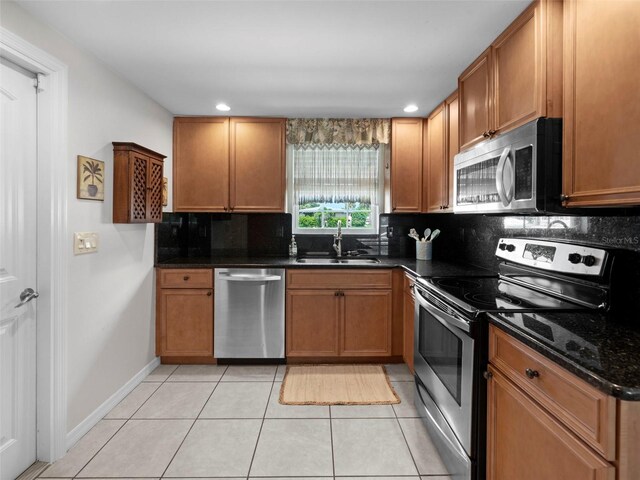 kitchen with light tile patterned flooring, sink, backsplash, dark stone counters, and stainless steel appliances