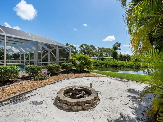 view of patio with a fire pit, a water view, and a lanai